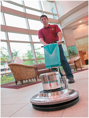 A ServiceMaster technician cleaning tile floors with specialty equipment