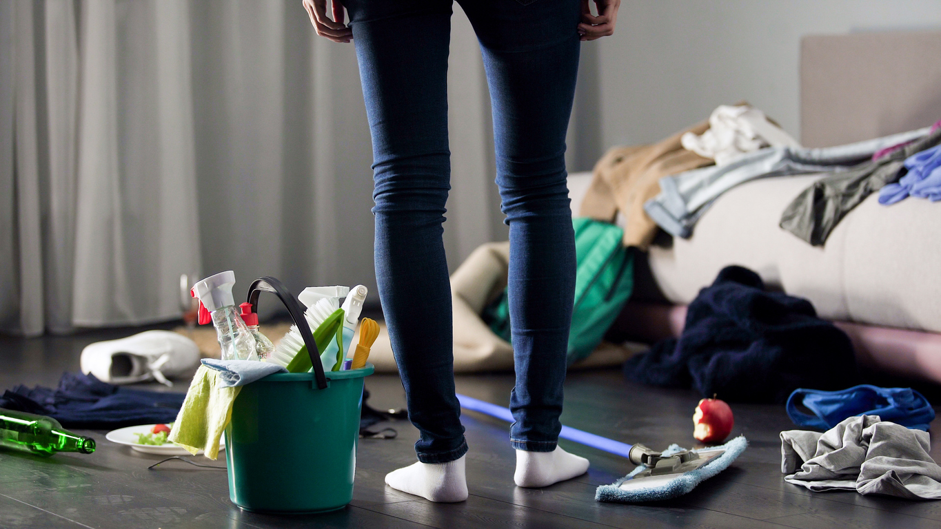 A person standing in front of clutter and cleaning supplies