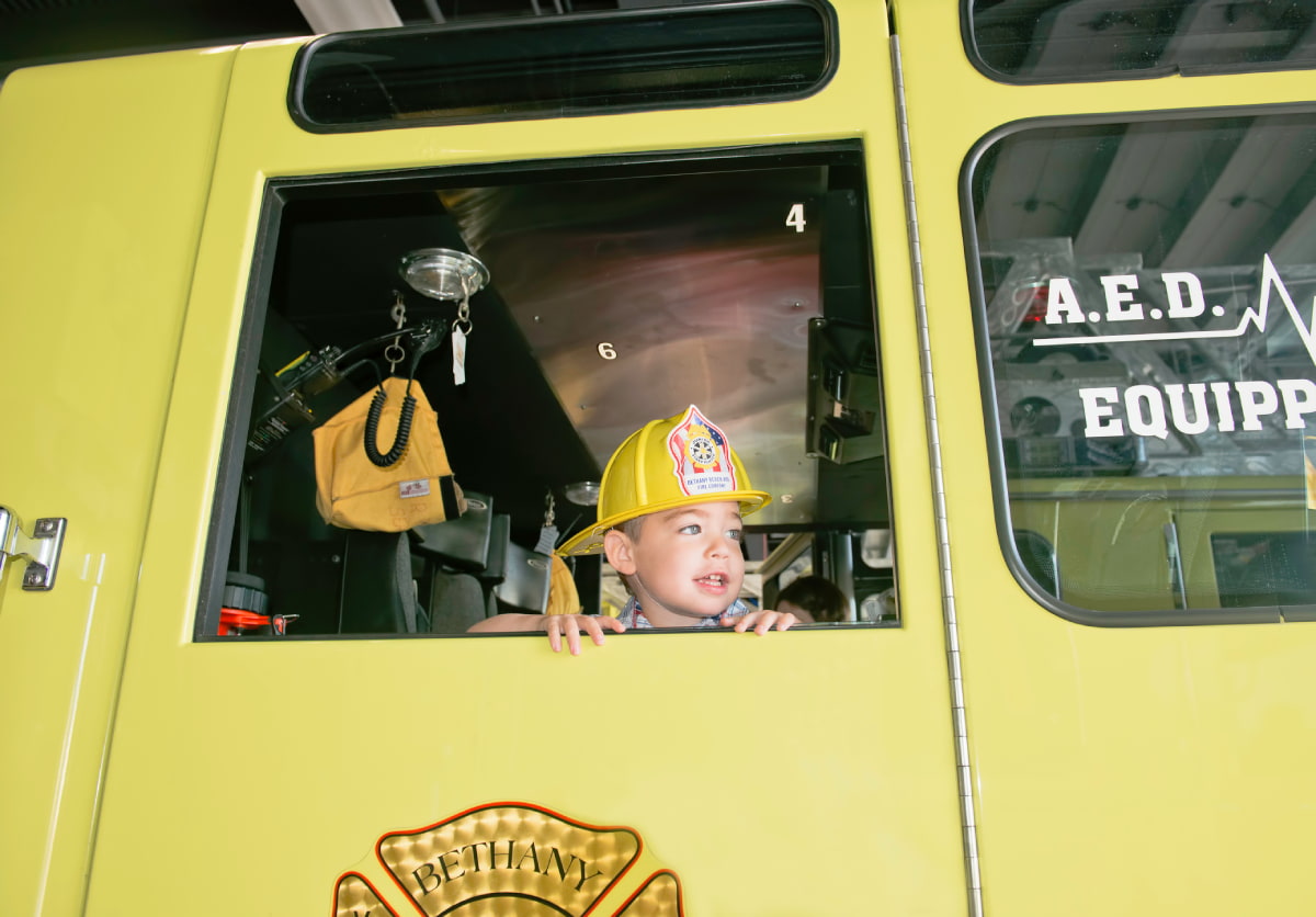 Boy sitting in a fire truck with a helmet