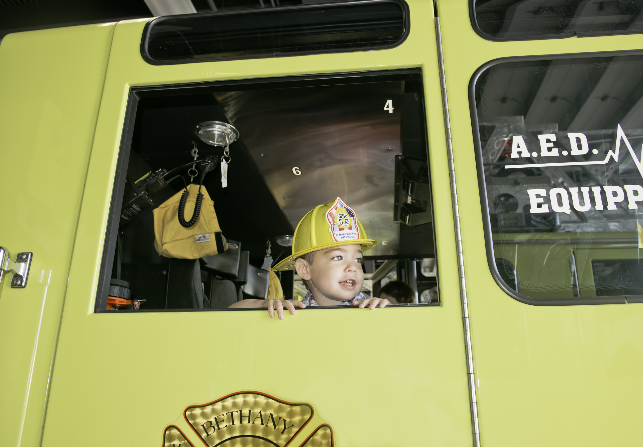 Boy sitting in a fire truck with a helmet